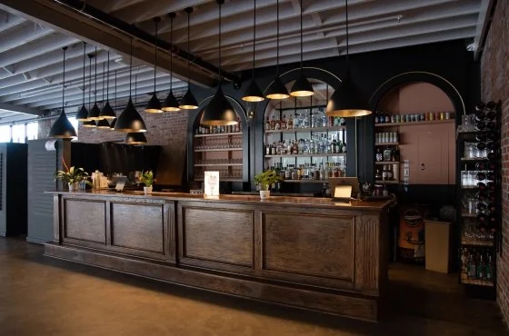 Dark wood bar with arched back bar and pendant lights