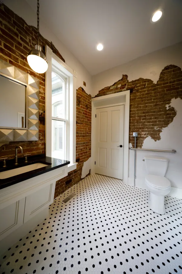 A bathroom with exposed brick walls and black-and-white hex tile