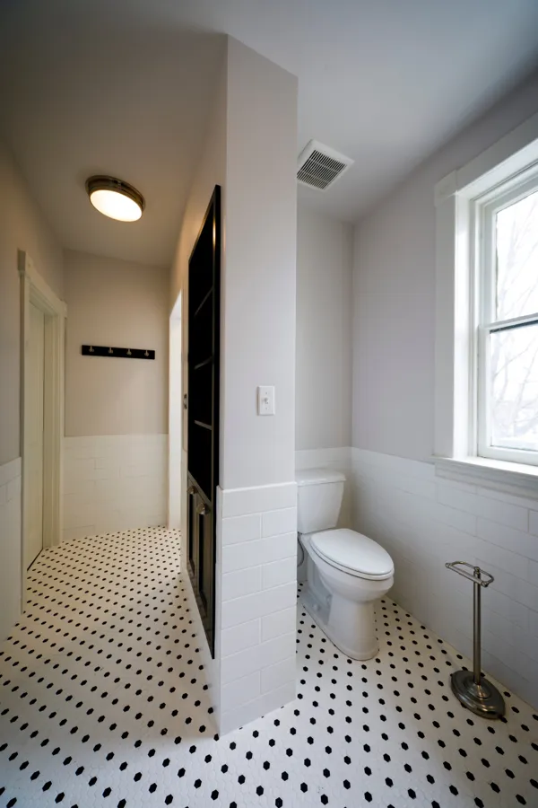 A bathroom with subway tile wainscot and black-and-white hex tile floor