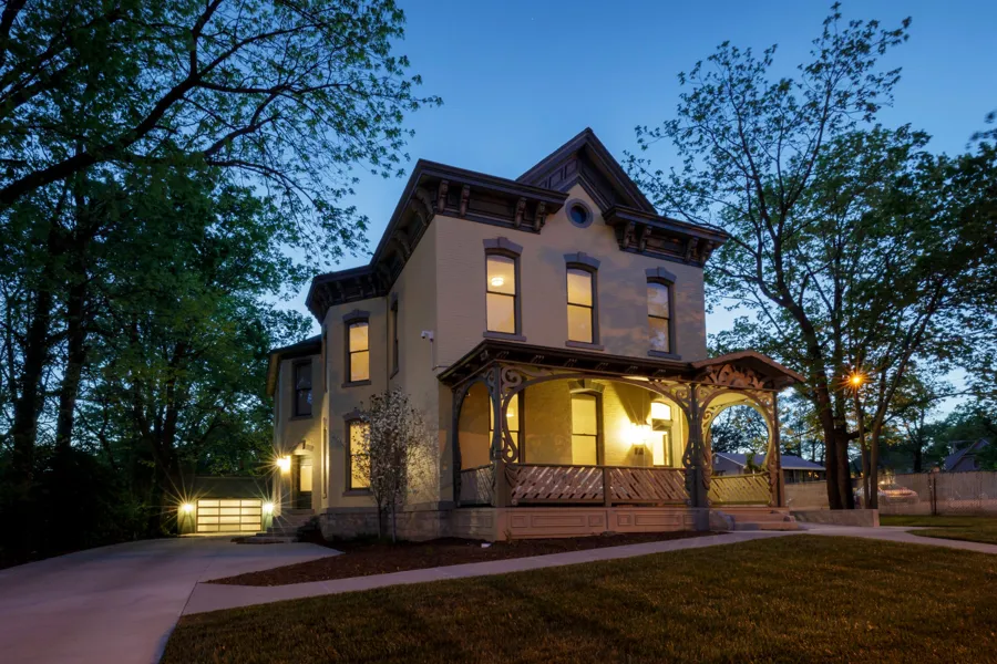 The house at dusk from the corner, with the porch, side entry and new garage lit up