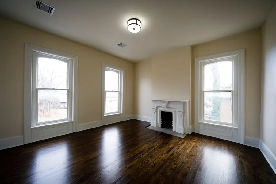 An upstairs room with a cast iron fireplace and tall arched windows