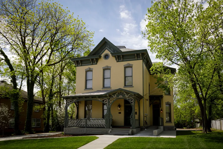 The restored Elkins House on a spring day, yellow brick with green trim and the curving Art Nouveau porch