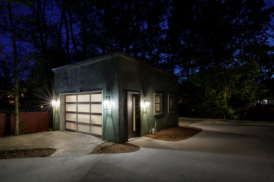 The renovated garage at night with a frosted glass door and wall lanterns