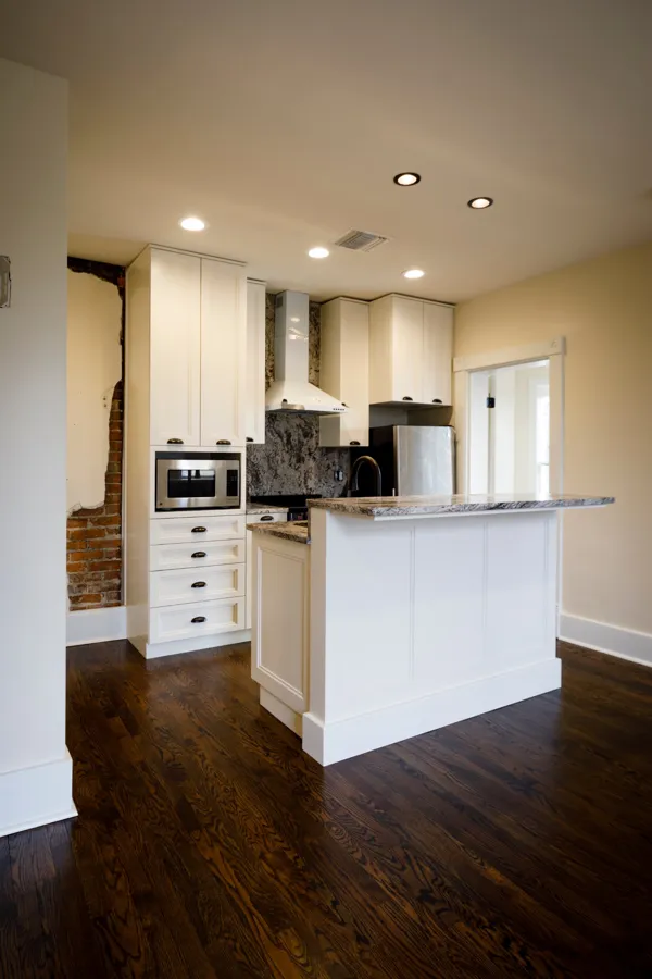 A kitchen with an island and a strip of original brick left exposed